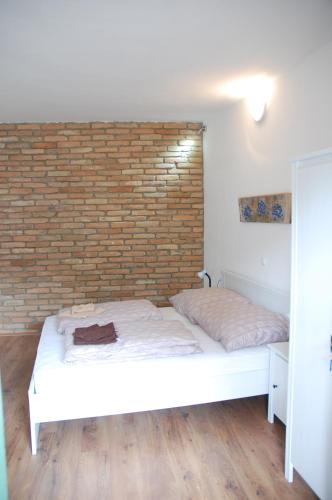 a bedroom with a brick wall and a white bed at Likaskalács in Regöly