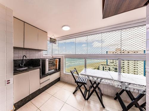 Vila BalneáriaにあるCantinho em Família - XF05Hのキッチン(テーブル付)、大きな窓が備わります。