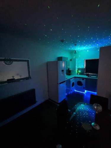 a kitchen with a white refrigerator and blue lights at Beautiful Modern Apartment on Wick Lane in London