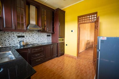 uma cozinha com armários de madeira e um frigorífico azul em Sky View Guest house em Batticaloa