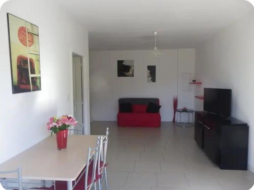 un salon avec une table et un canapé rouge dans l'établissement Gîte au coeur d'une oliveraie, à Sartène