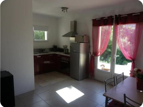 une cuisine avec un réfrigérateur, une table et une fenêtre dans l'établissement Gîte au coeur d'une oliveraie, à Sartène