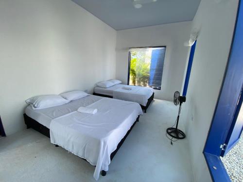 2 bedden in een witte kamer met een raam bij Villa Santorini in Cumaral