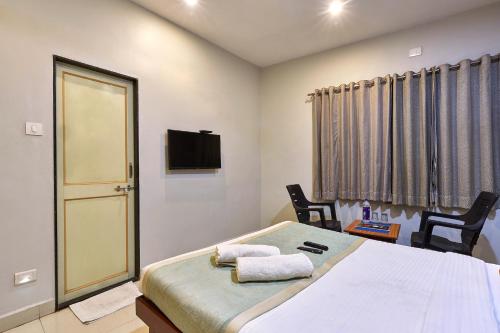 a bedroom with a bed with two chairs and a television at Hotel Popillon, Kolhapur in Kolhapur