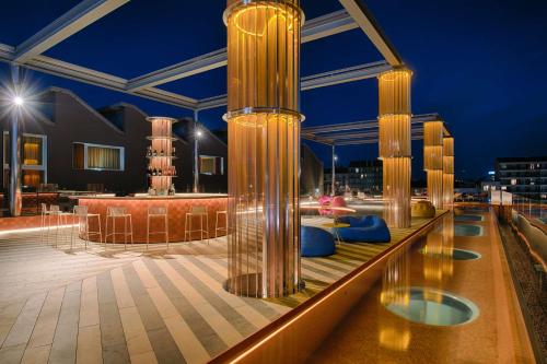 un toit-terrasse avec colonnes et sièges bleus dans un bâtiment dans l'établissement Nhow Milan, à Milan