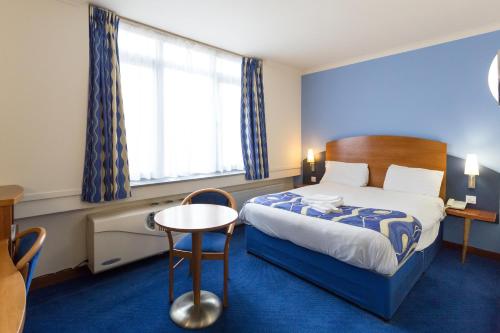a hotel room with a bed and a table at London - Wembley International Hotel in London
