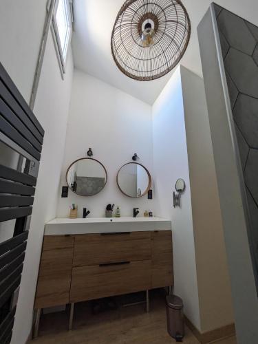 une salle de bain avec un lavabo et deux miroirs dans l'établissement La maison Matthieu, à Bédoin