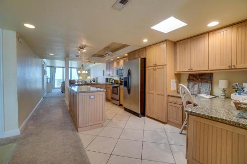 a large kitchen with wooden cabinets and a refrigerator at Spectacular Sunsets at this Beachfront Condo in Bradenton Beach