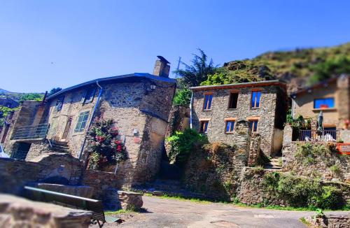 un vieux bâtiment en pierre avec des fenêtres bleues sur une colline dans l'établissement Mountain Village Studio en Nohèdes pour 2, à Nohèdes