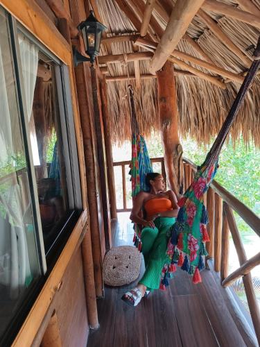 a man sitting in a hammock in a cabin at Kite Eco House Salinas del rey in Salina de Rey