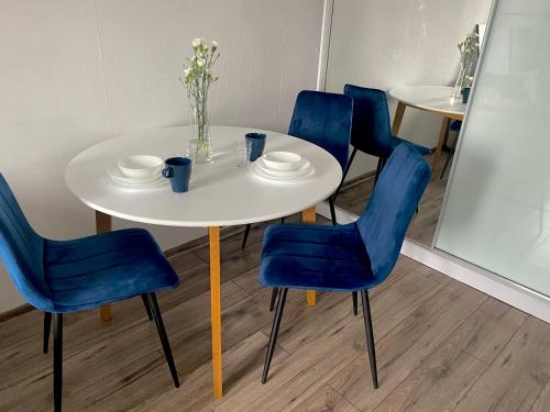 - une table blanche et des chaises bleues dans la chambre dans l'établissement Jasnogórska, à Częstochowa