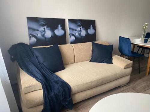 eine Couch in einem Wohnzimmer mit zwei Bildern an der Wand in der Unterkunft Jasnogórska in Częstochowa