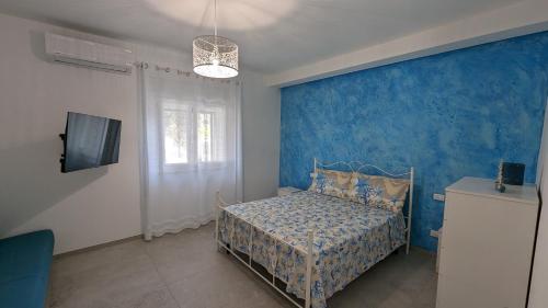 1 dormitorio con cama y pared azul en Leporano villa MADIA con piscina, Taranto, en Leporano Marina