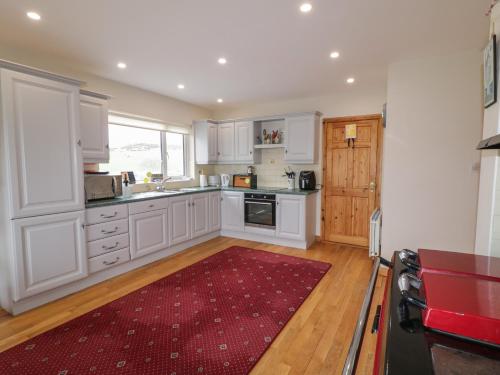 a kitchen with white cabinets and a red rug at Ranny Roe in Fanad