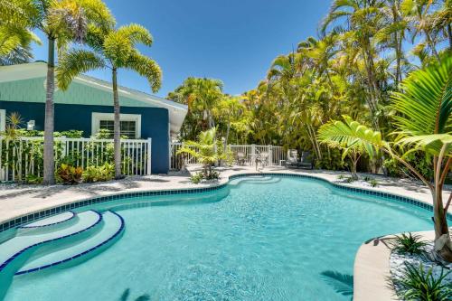 a swimming pool with palm trees in front of a house at A Blue Lagoon on Anna Maria with Heated Pool in Anna Maria