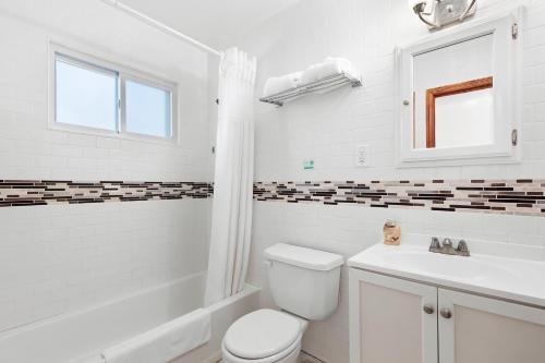 a white bathroom with a toilet and a sink at Bay Watch Hotel and Marina in Hampton Bays
