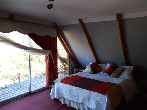 a bedroom with a bed and a large window at Cabaña Elu in Llico