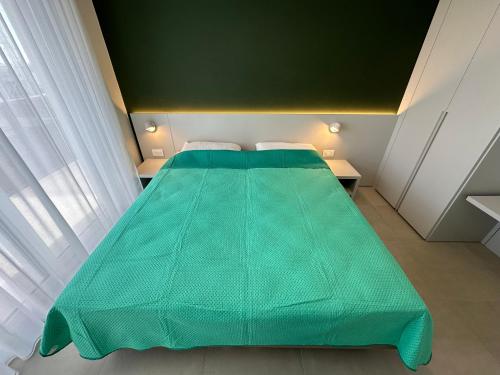 a large green bed in a small room at Woody Green Charming Apartments - Agenzia Cocal in Caorle