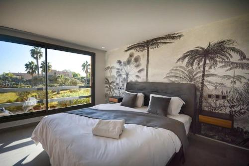 ein Schlafzimmer mit einem großen Bett mit einem großen Fenster in der Unterkunft Luxueux Duplex 2CH dans une magnifique résidence in Marrakesch