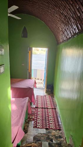 a green room with two beds and a window at Taam Al beeyout in Naj‘ al Maḩaţţah