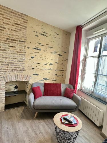 un salon avec un canapé et un mur de briques dans l'établissement Charmant studio hyper centre, à Angers