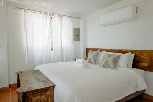 een slaapkamer met een wit bed en een houten hoofdeinde bij Ocean view studio in Pelada! in Nosara