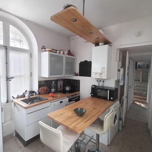 a kitchen with white cabinets and a wooden counter top at ILE SAINT LOUIS 2 CHAMMBRES 2 SALLE DE BAINS PARKING in Paris
