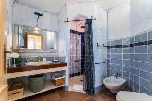 W wyłożonej niebieskimi kafelkami łazience znajduje się umywalka i toaleta. w obiekcie B&B Calata Di Soli w mieście Miniera dellʼArgentiera