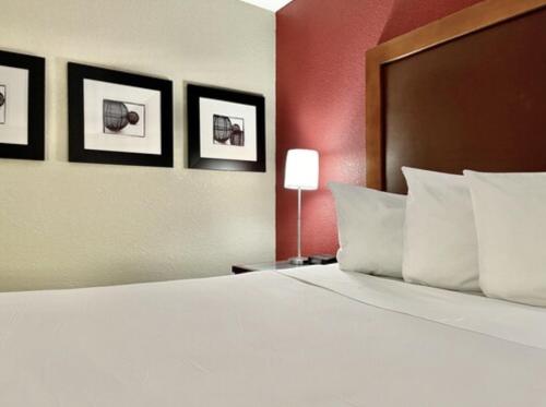 um quarto com uma grande cama branca com três fotografias na parede em FairBridge Inn & Suites Fort Wayne em Fort Wayne