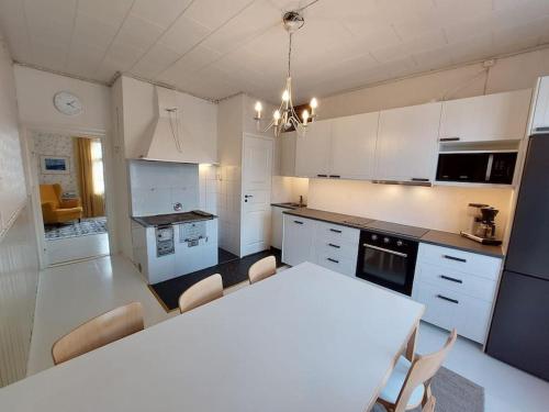 uma cozinha branca com uma mesa e cadeiras brancas em Charming wooden house apartment 48 m2 em Turku