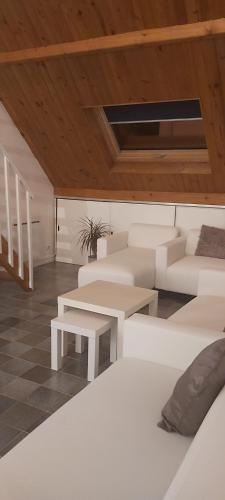 ein Wohnzimmer mit weißen Möbeln und Holzdecken in der Unterkunft Le Jardin d'Eden in Château-Thierry