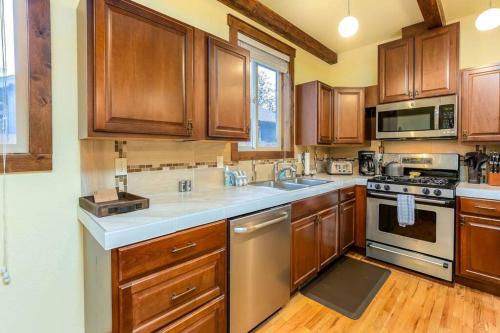 a kitchen with wooden cabinets and stainless steel appliances at Walk to Everything Bikes AC Dog Friendly in Bend