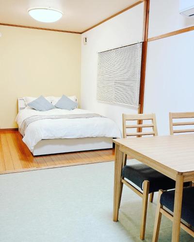 Hita hostel - Vacation STAY 07583v في هيتا: غرفة نوم بسرير وطاولة وكراسي
