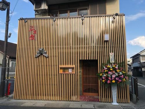 um edifício de madeira com uma porta e flores no passeio em Hita hostel - Vacation STAY 07583v em Hita