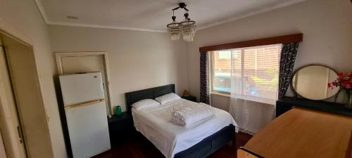 1 dormitorio con 1 cama blanca y nevera en Charming Brick Homestay Room in Northam en Northam