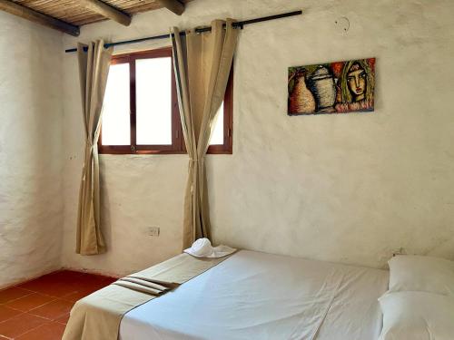 1 dormitorio con cama blanca y ventana en ETNIA LODGE, en Minca