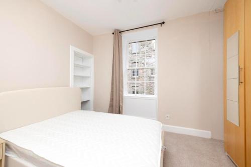 ein weißes Schlafzimmer mit einem Bett und einem Fenster in der Unterkunft Royal Mile Apartments in Edinburgh