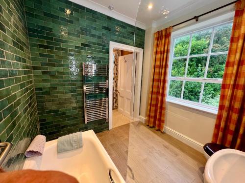 a bathroom with a tub and a sink and a window at The Mill House in Santon