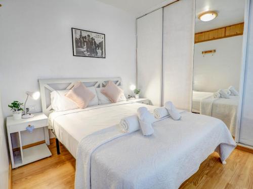a white bedroom with two beds and a mirror at Carmen Apartment by Hello Homes Sitges in Sitges