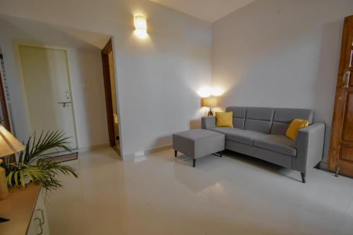 a living room with a gray couch and yellow pillows at HomeSlice Whitefield in Bengaluru