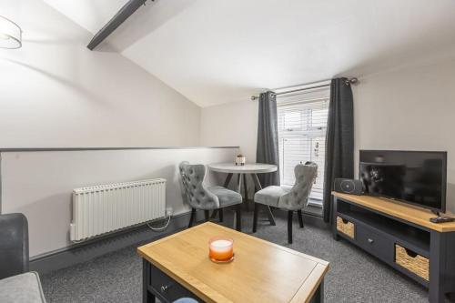 a living room with a table and a tv at Rugby Coach House, Central location, 5 star rating in Rugby