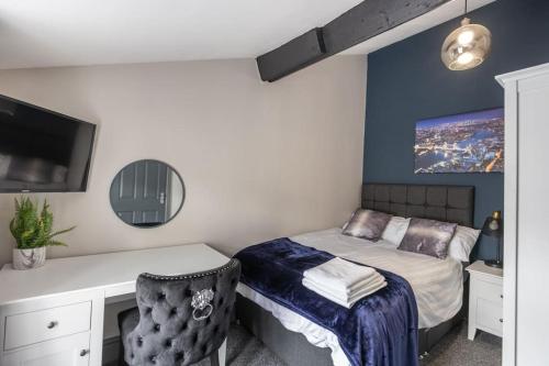 a bedroom with a bed and a desk with a computer at Rugby Coach House, Central location, 5 star rating in Rugby