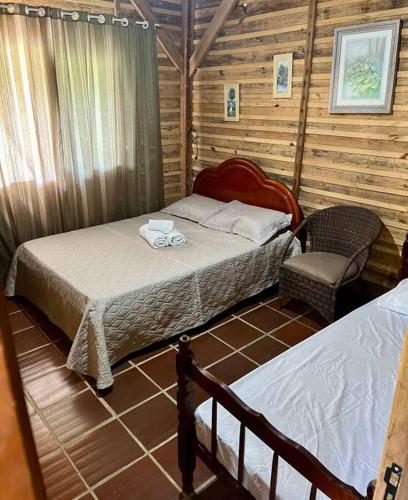 ein Schlafzimmer mit 2 Betten und einem Stuhl in einer Hütte in der Unterkunft Chalé canadense em Rio Bonito in Rio dos Cedros