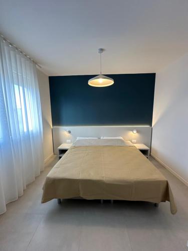a bedroom with a large bed and a blue wall at Woody Green Charming Apartments - Agenzia Cocal in Caorle