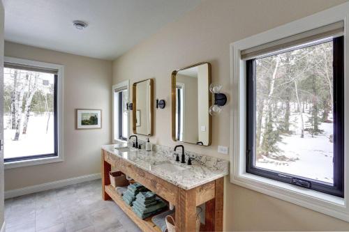 a bathroom with two sinks and two large windows at The Juniper - Hot tub in Lead