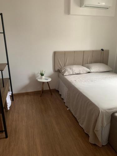 1 dormitorio con cama y mesa pequeña en Apartamento pé na areia en Barra Velha