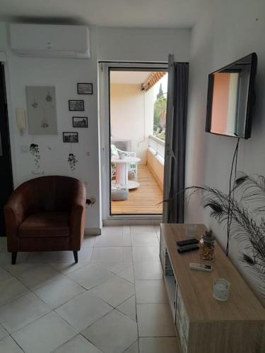 - un salon avec une chaise, un canapé et une télévision dans l'établissement Charmant studio lumineux avec parking privé, à Saint-Raphaël