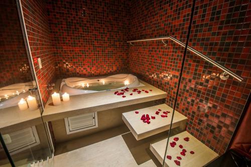 y baño con bañera y ducha con azulejos rojos. en Motel I Love Pelotas, en Pelotas