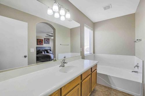 a bathroom with a sink and a tub and a mirror at Jill's Goodyear Getaway in Goodyear