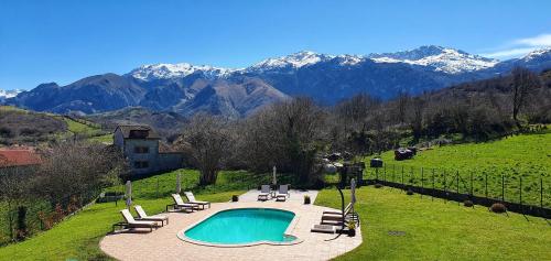 a swimming pool in a field with mountains in the background at Refugio del Cares in Ortiguero